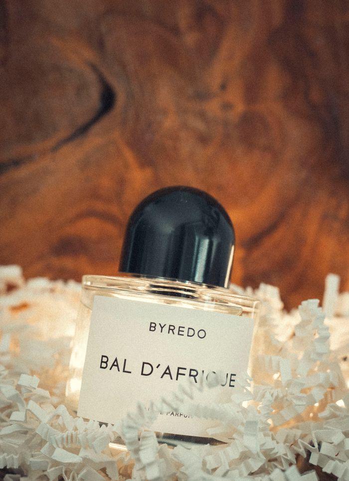 programs-01 Stylish product photo of Byredo Bal d'Afrique perfume bottle amidst paper shreds, radiating luxury.