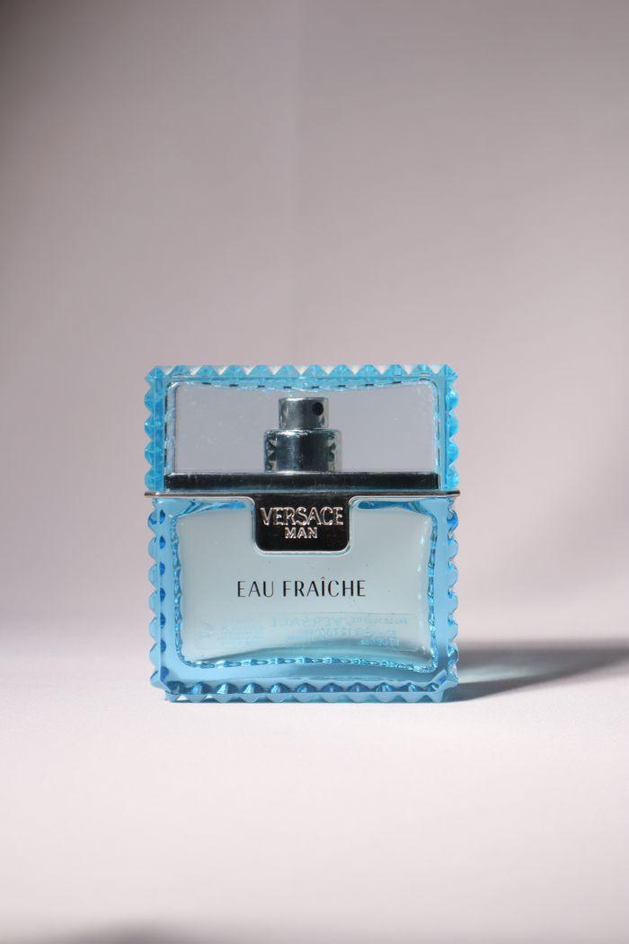 about-img Stylish blue bottle of Versace Eau Fraîche perfume isolated on a soft light background.