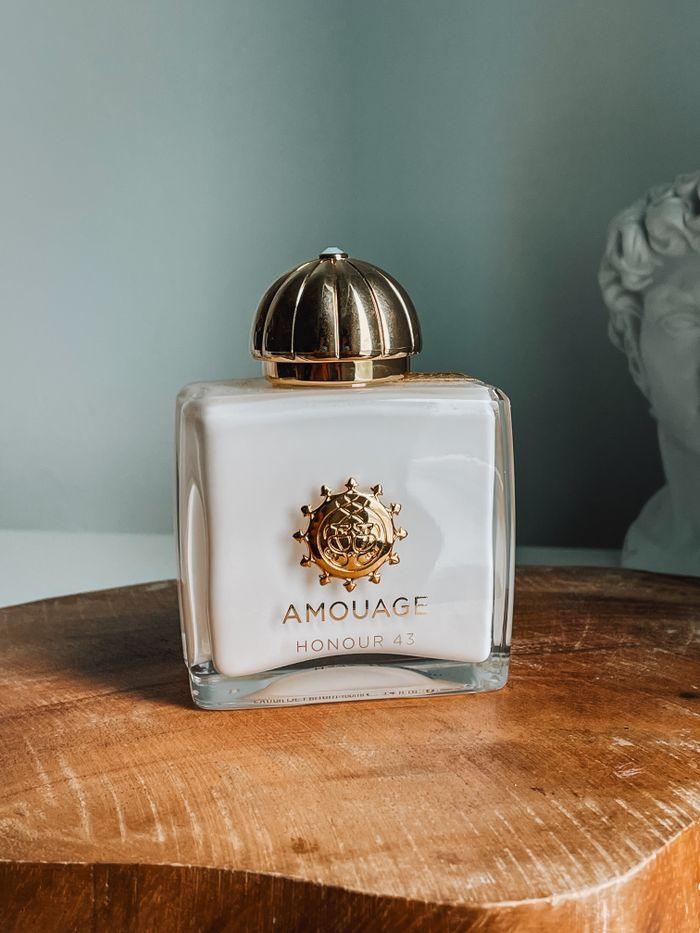 gallery-img-01 Elegant Amouage Honour 42 perfume bottle on wooden surface with artistic backdrop.