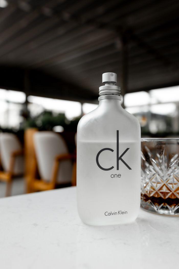 hero-gallery-01 Sophisticated CK One perfume bottle with glass, set on outdoor cafe table.